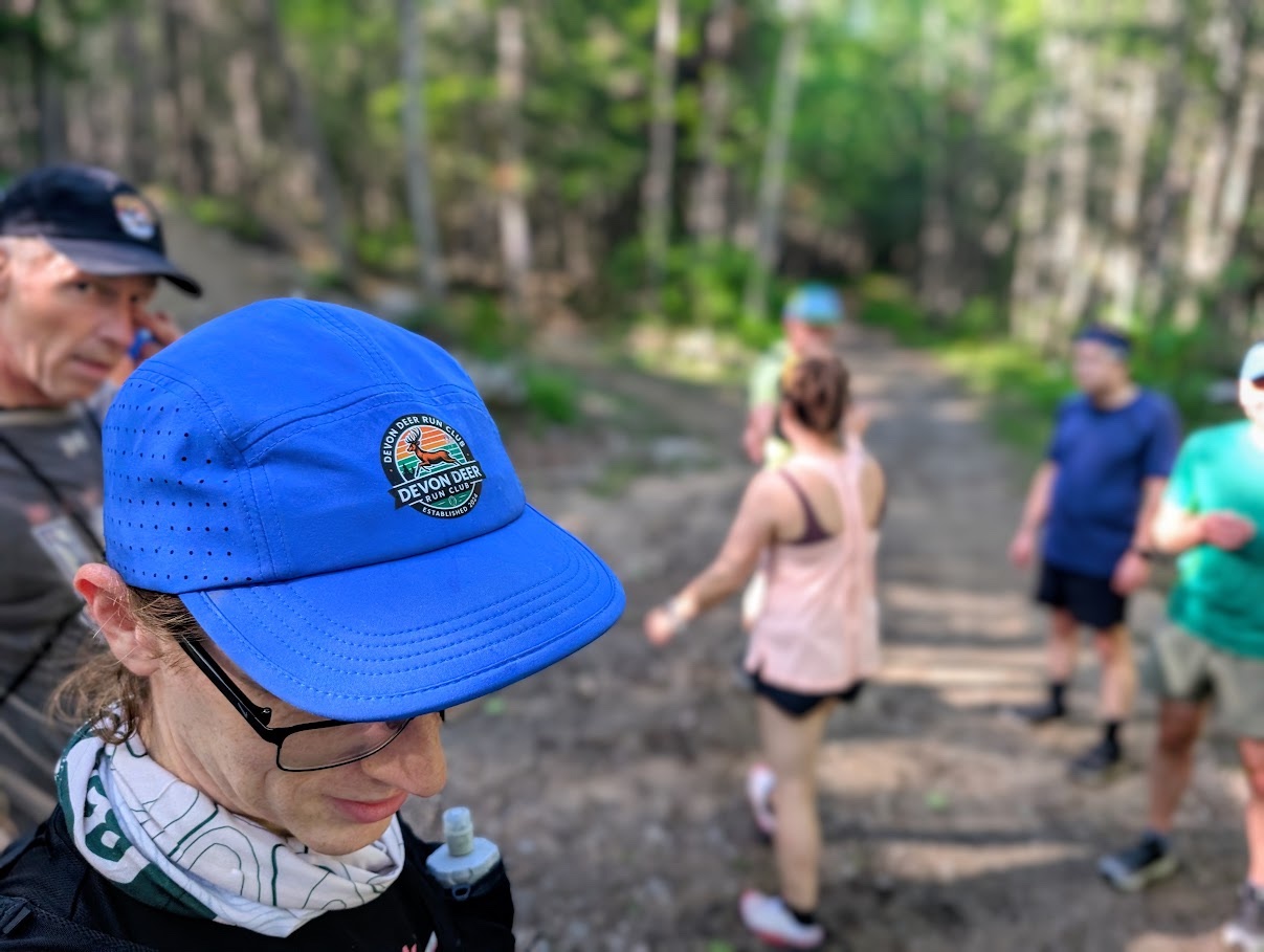 Une personne porte une casquette de course Devon Deer bleu vif pendant un regroupement au parc Odell.